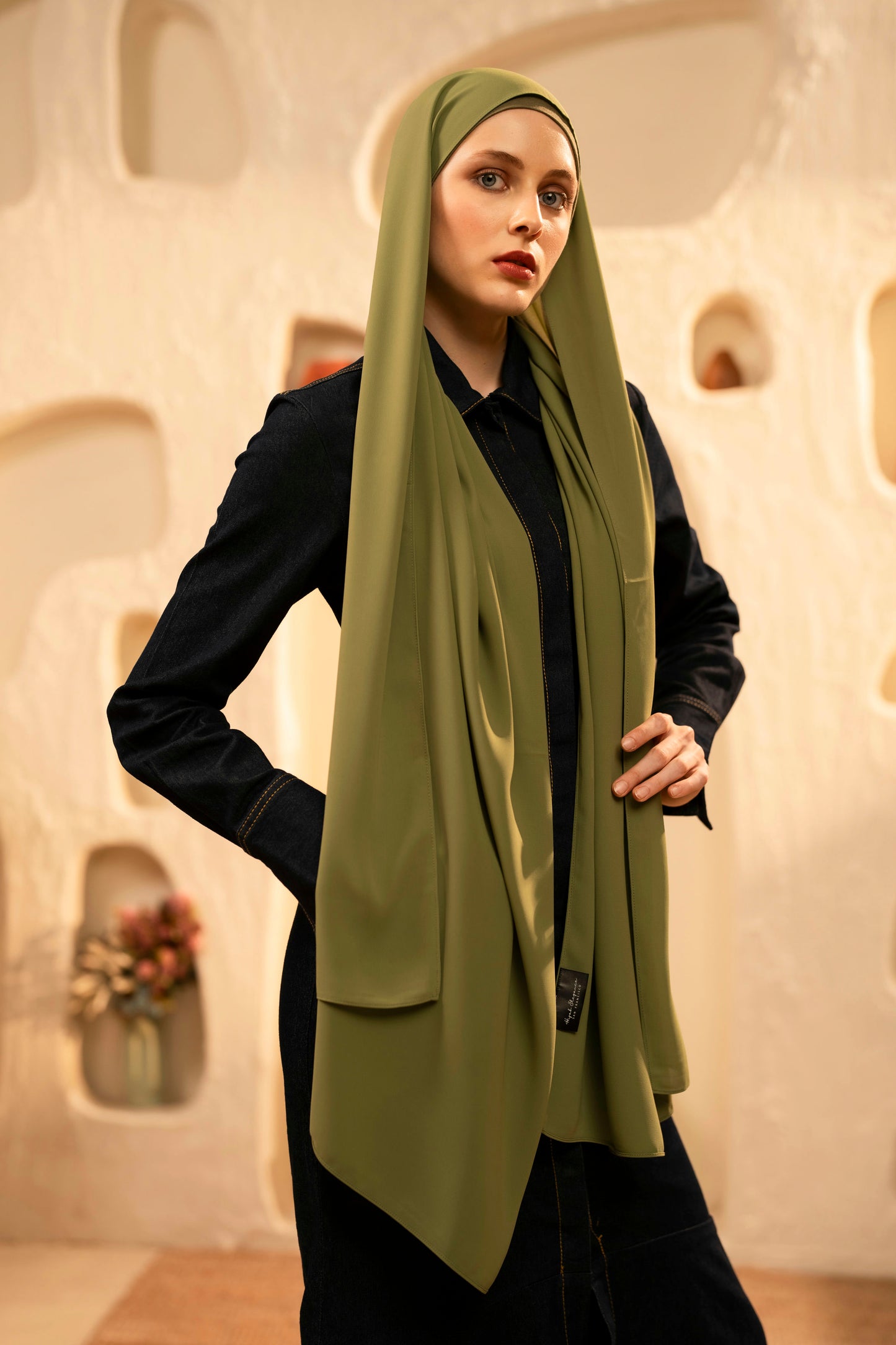 Woman wearing a green hijab in an indoor setting with decorative elements - olive green