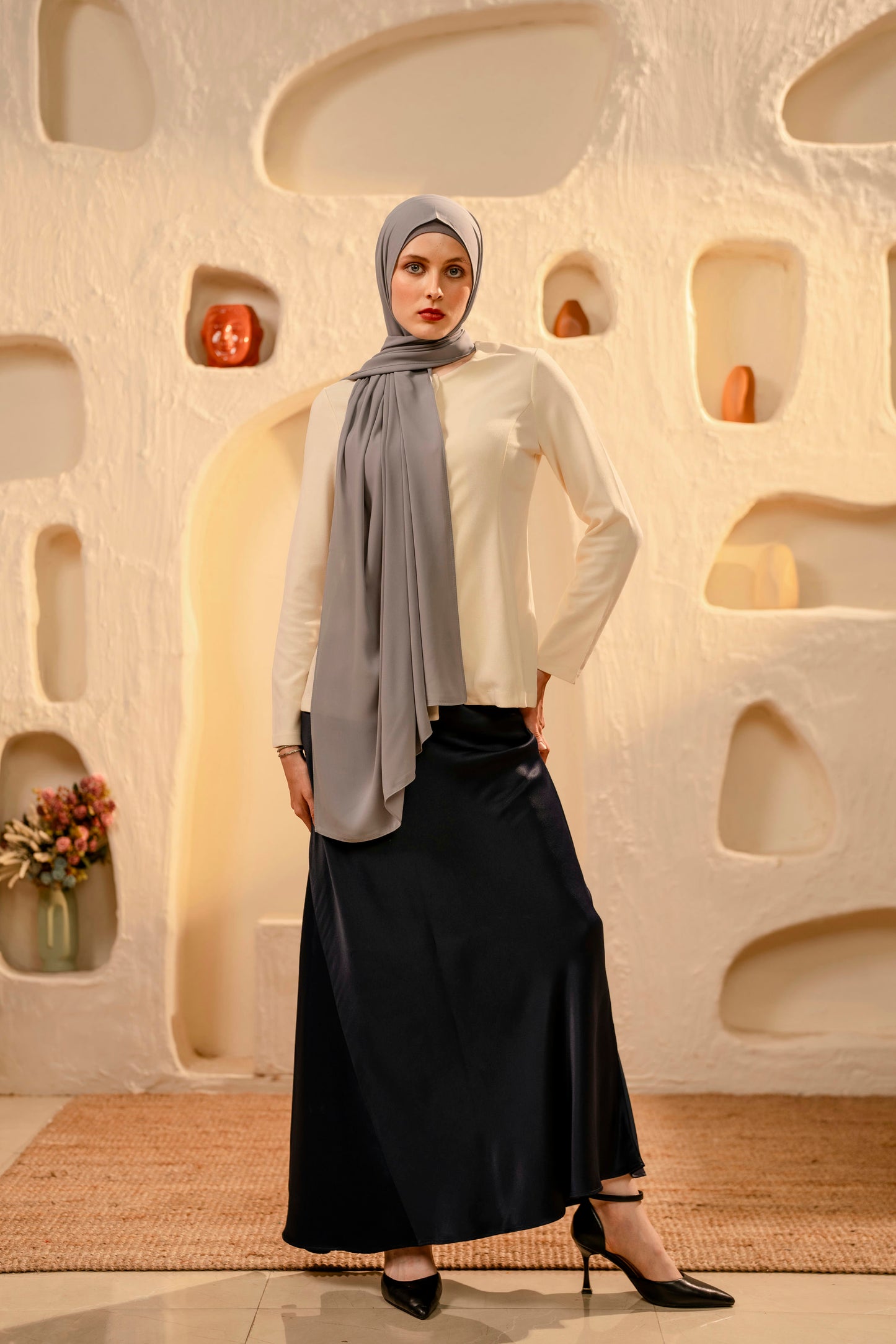 Woman wearing a hijab and dark skirt in a modern interior setting - gray