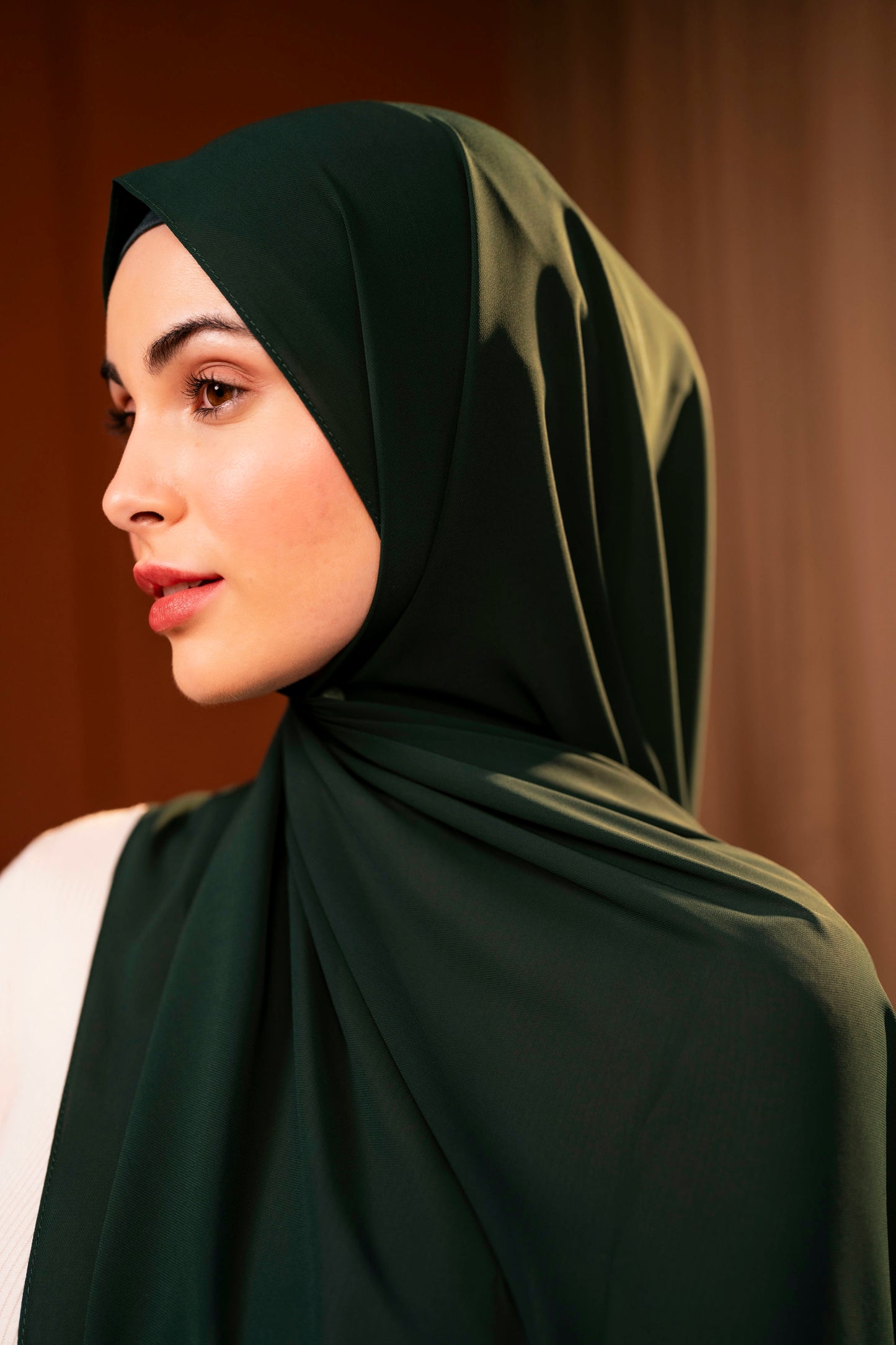 Woman wearing a dark green hijab against a dark background - Forest Green