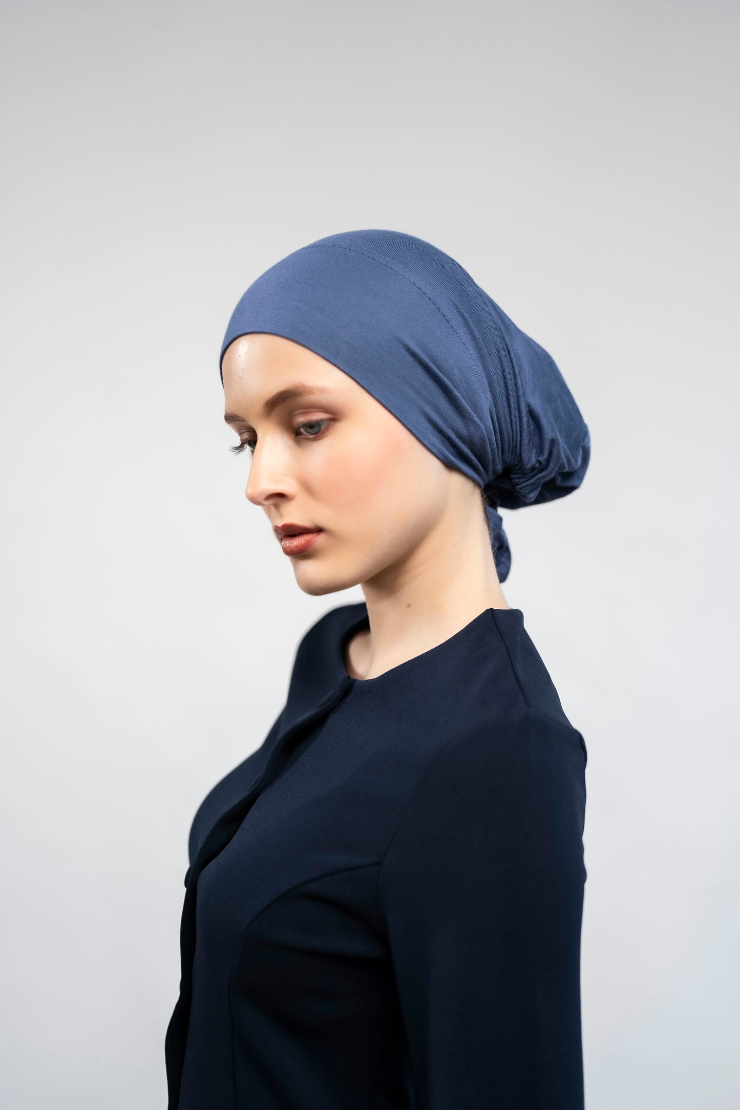 Woman wearing a blue headscarf against a plain background