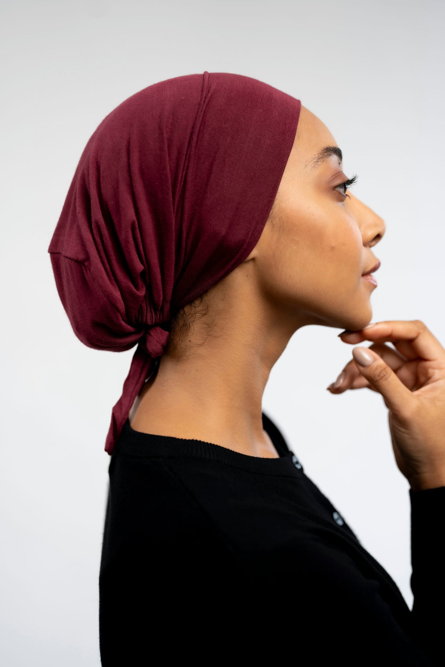 Woman wearing a burgundy headscarf against a light background - maroon
