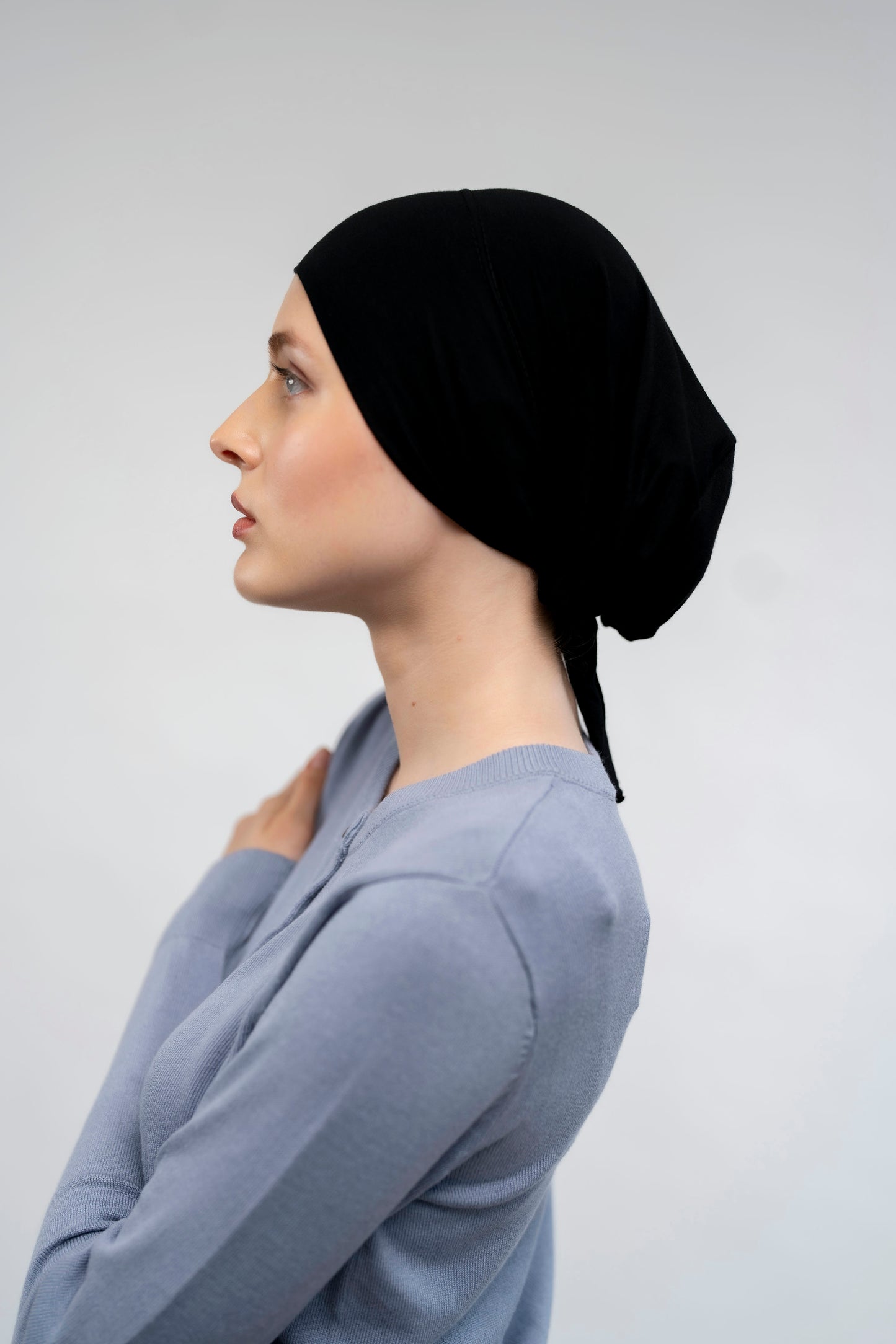 Woman wearing a black headscarf against a plain background