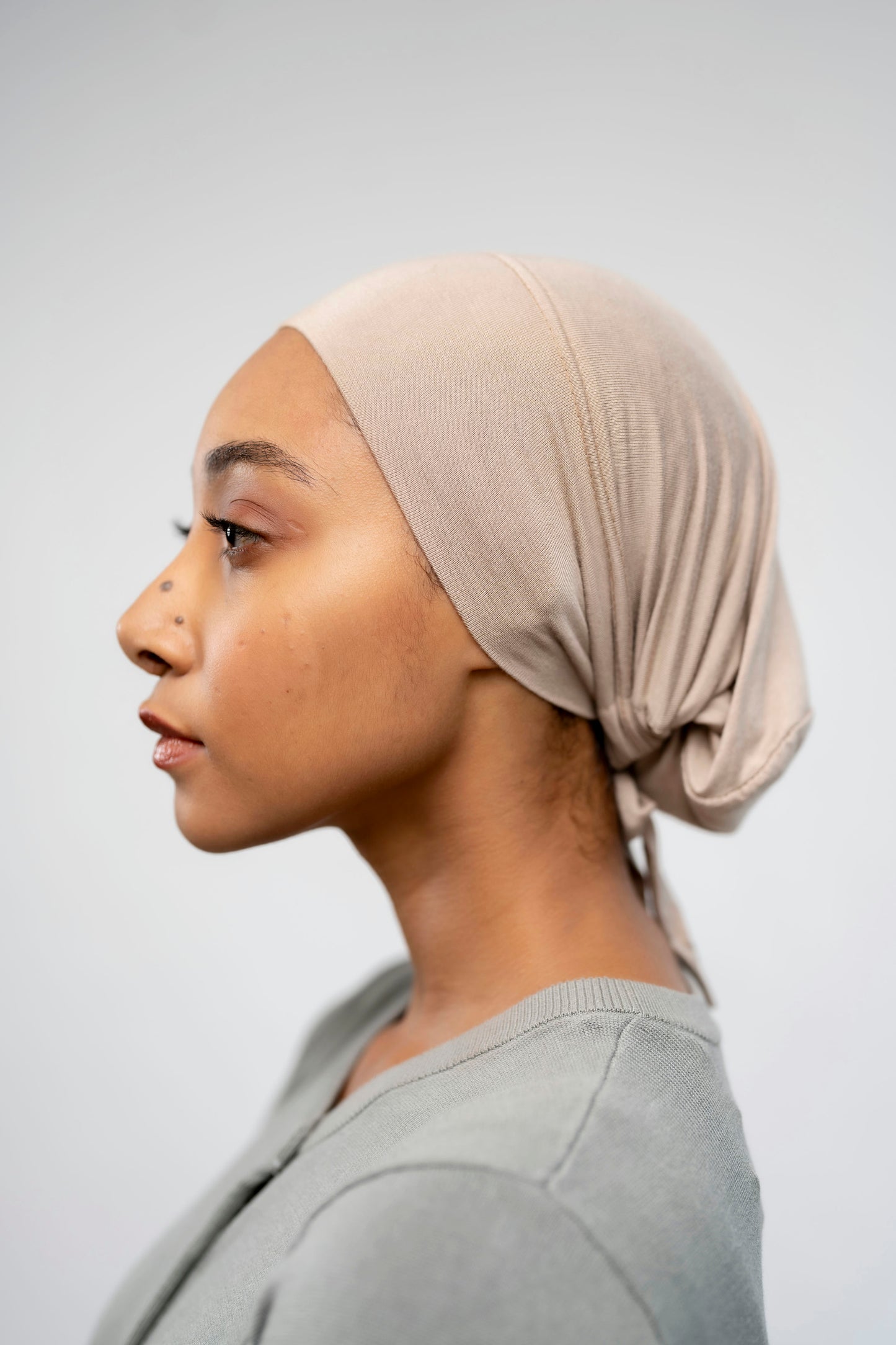 Woman wearing a beige headscarf against a plain background - buttercream