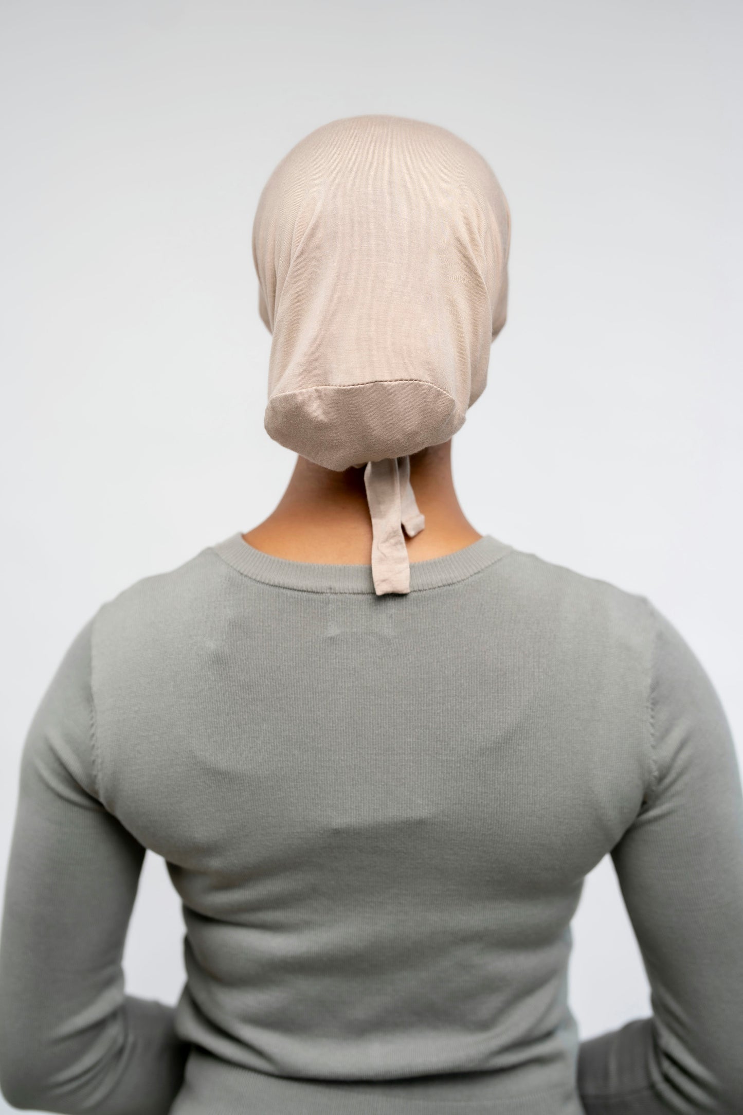 Person wearing a beige headscarf on a plain background - buttercream