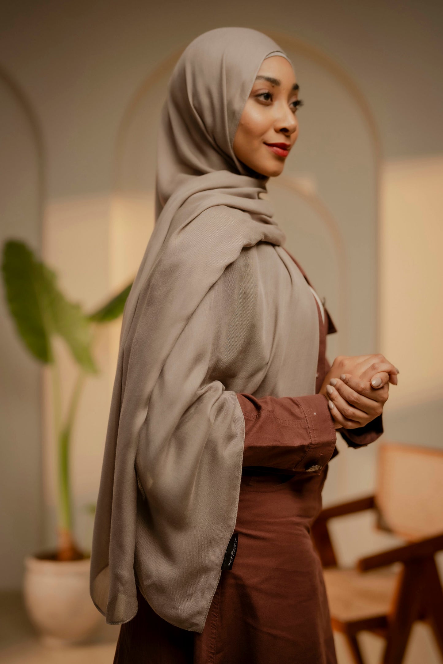Woman wearing a tan hijab and brown outfit in an indoor setting