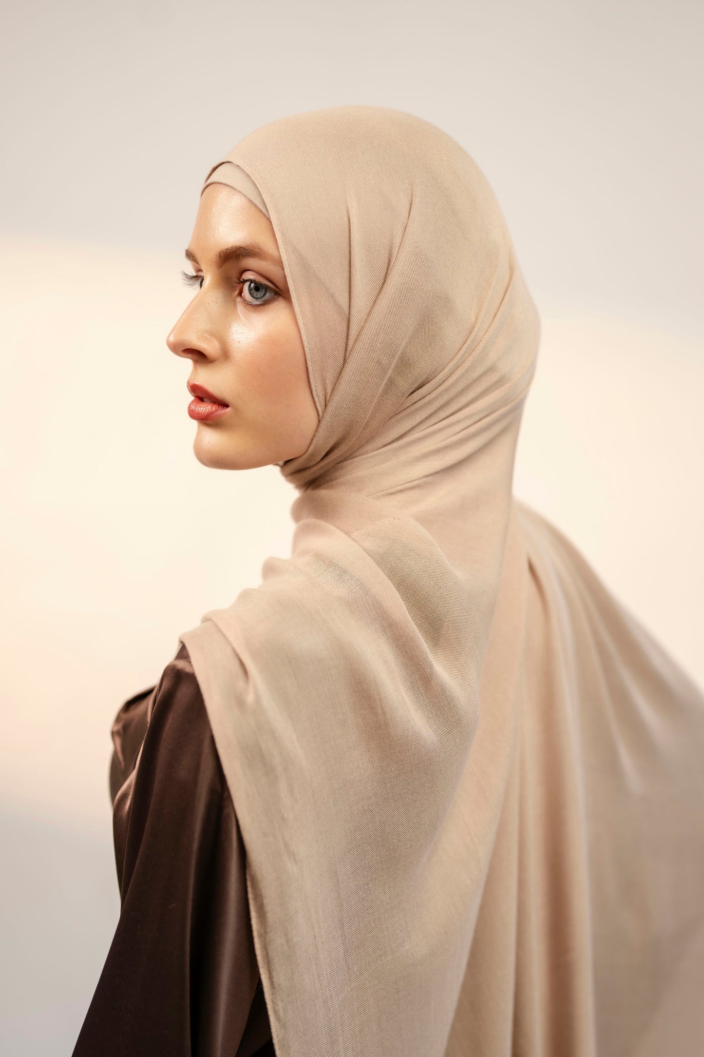 Woman wearing a beige hijab against a plain background - nude