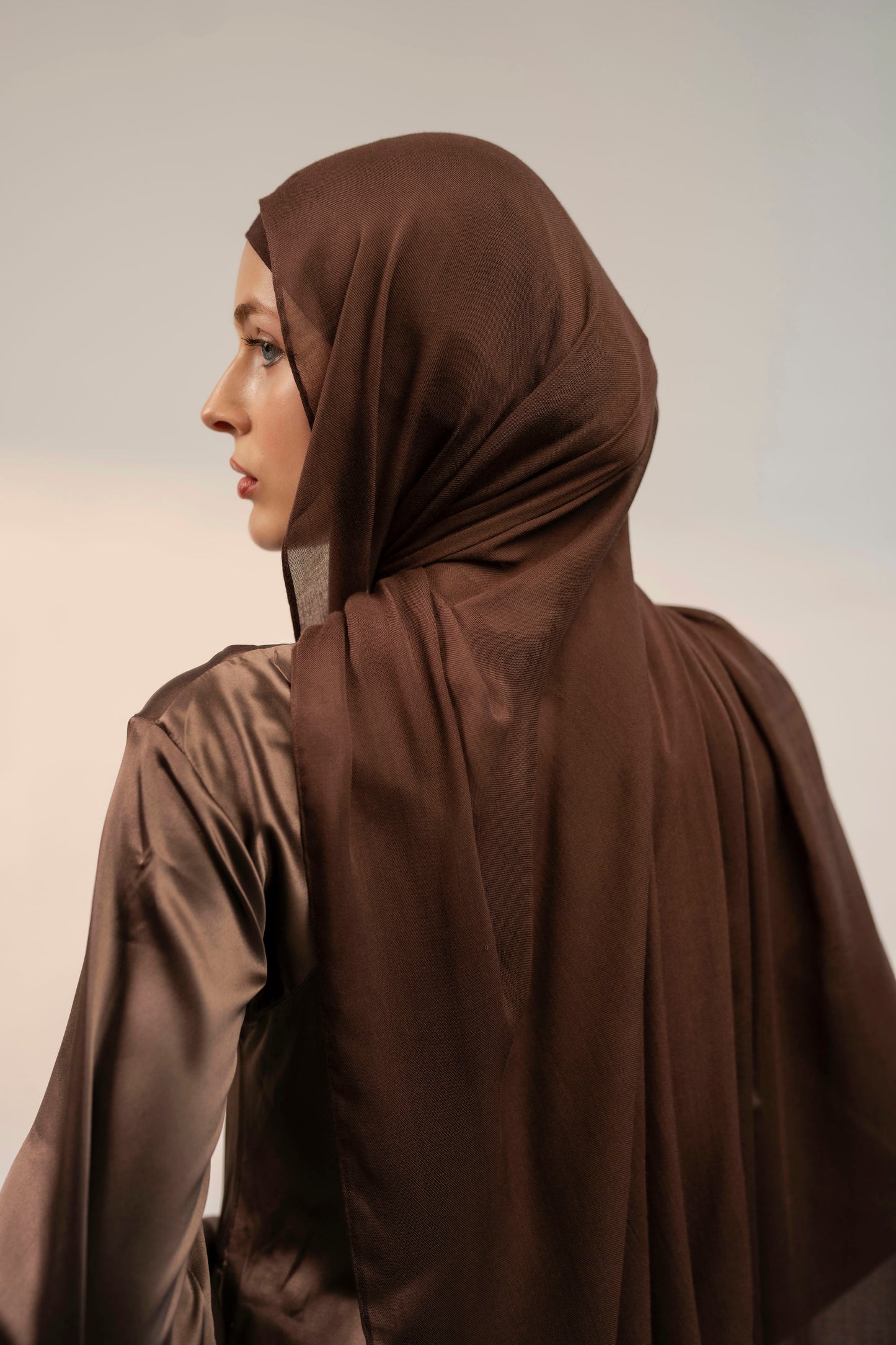 Woman wearing a brown hijab against a plain background - coffee brown