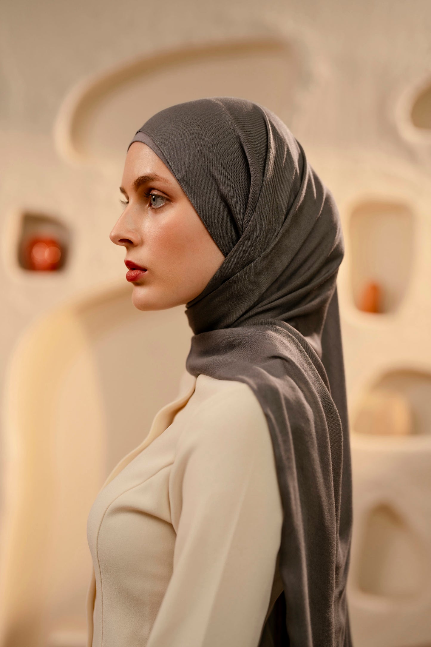 Woman wearing a warm gray hijab in an indoor setting with neutral colors