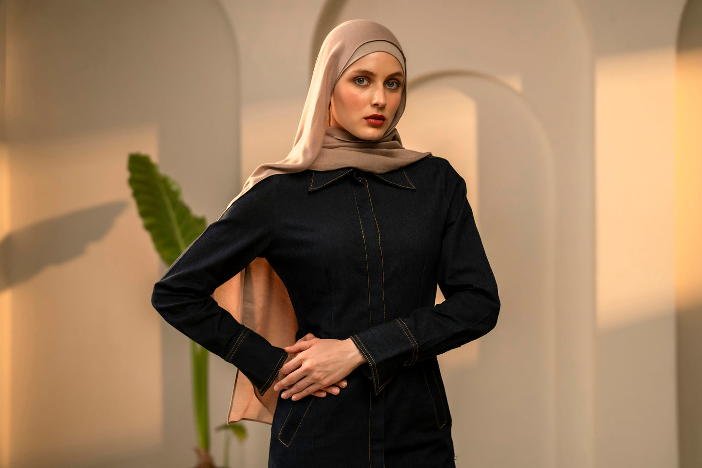 Woman wearing a dark outfit and beige hijab against a neutral background - mocha
