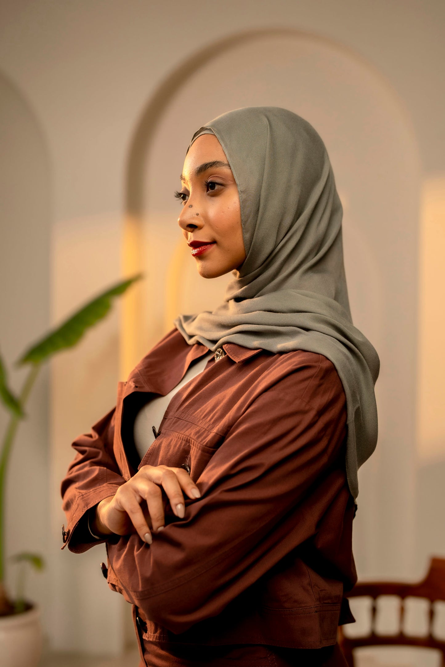 Woman wearing a hijab and brown jacket in an indoor setting - sage green