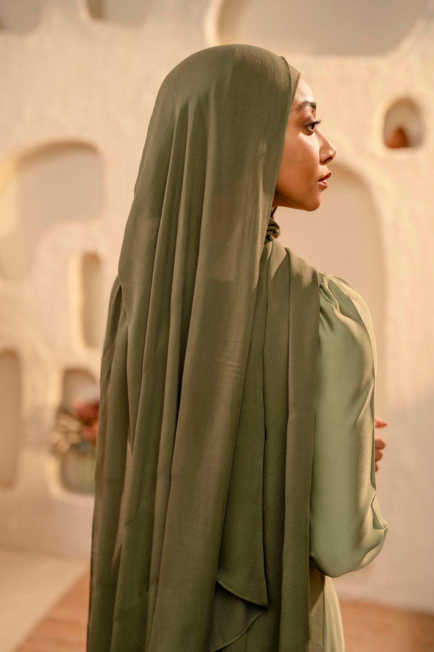 Woman wearing a green hijab and dress in a desert setting - olive green