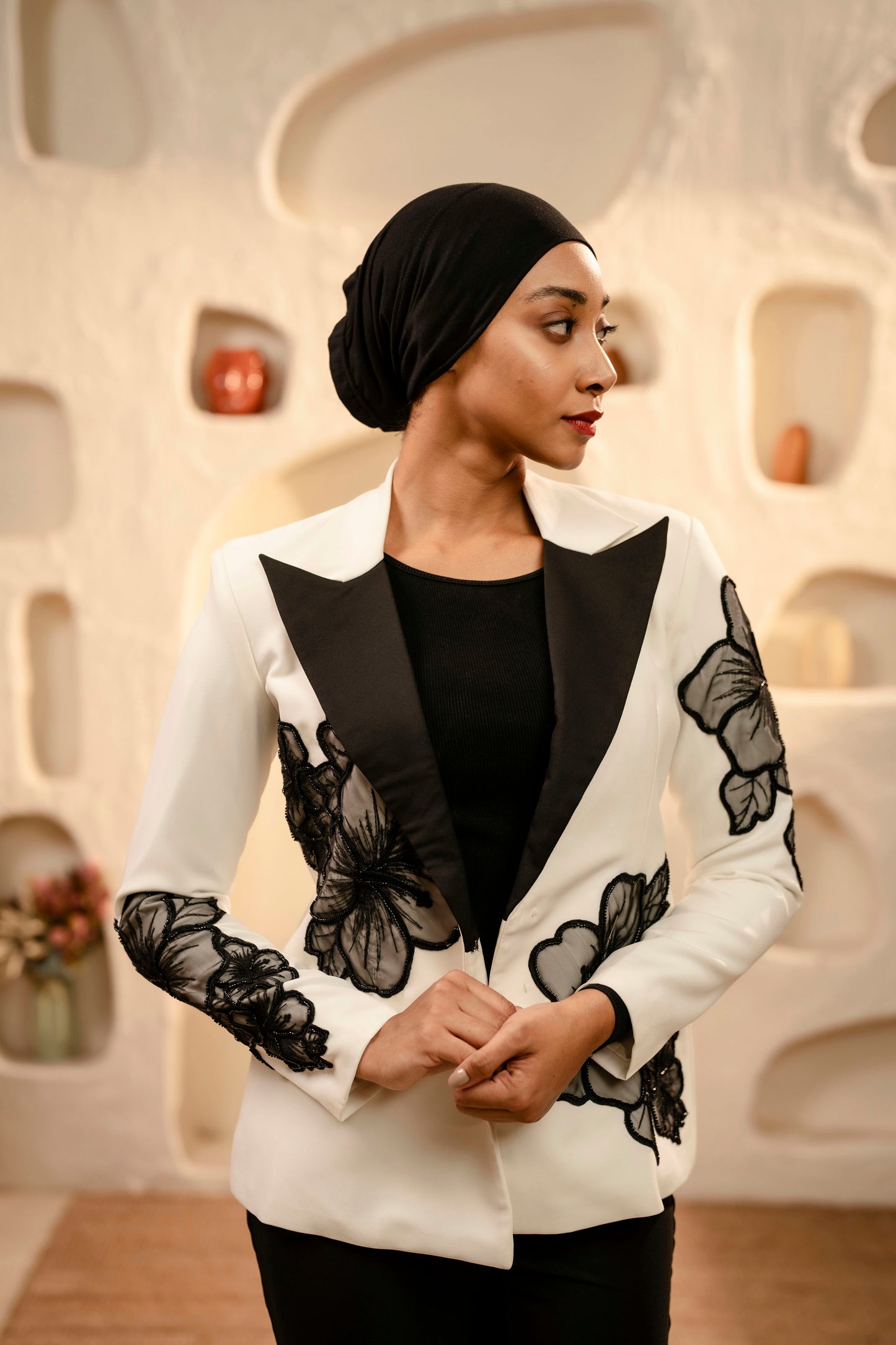 Woman wearing a white blazer with black butterfly patterns in an indoor setting