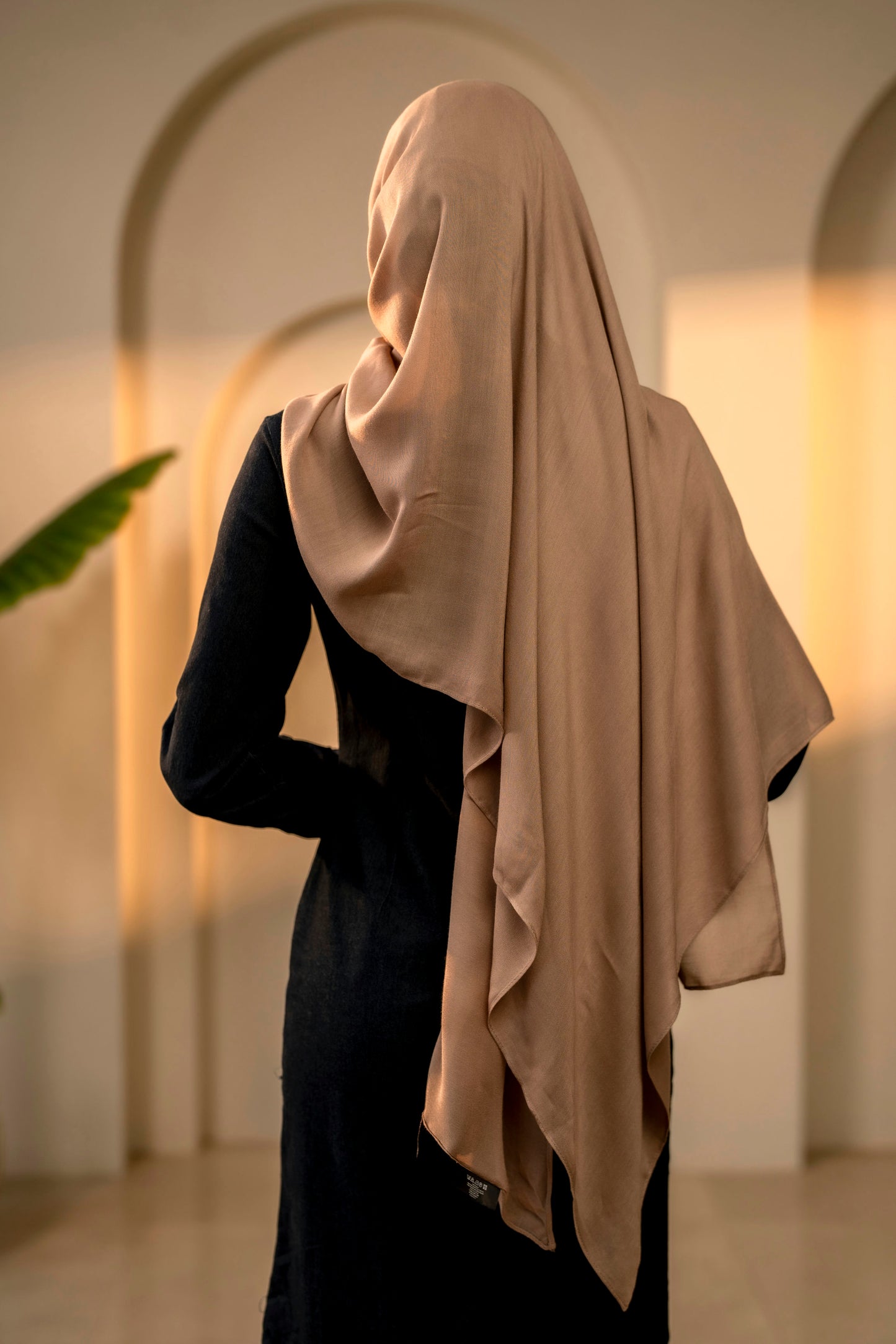 Person wearing a beige hijab in an indoor setting with arches and warm lighting - mocha color