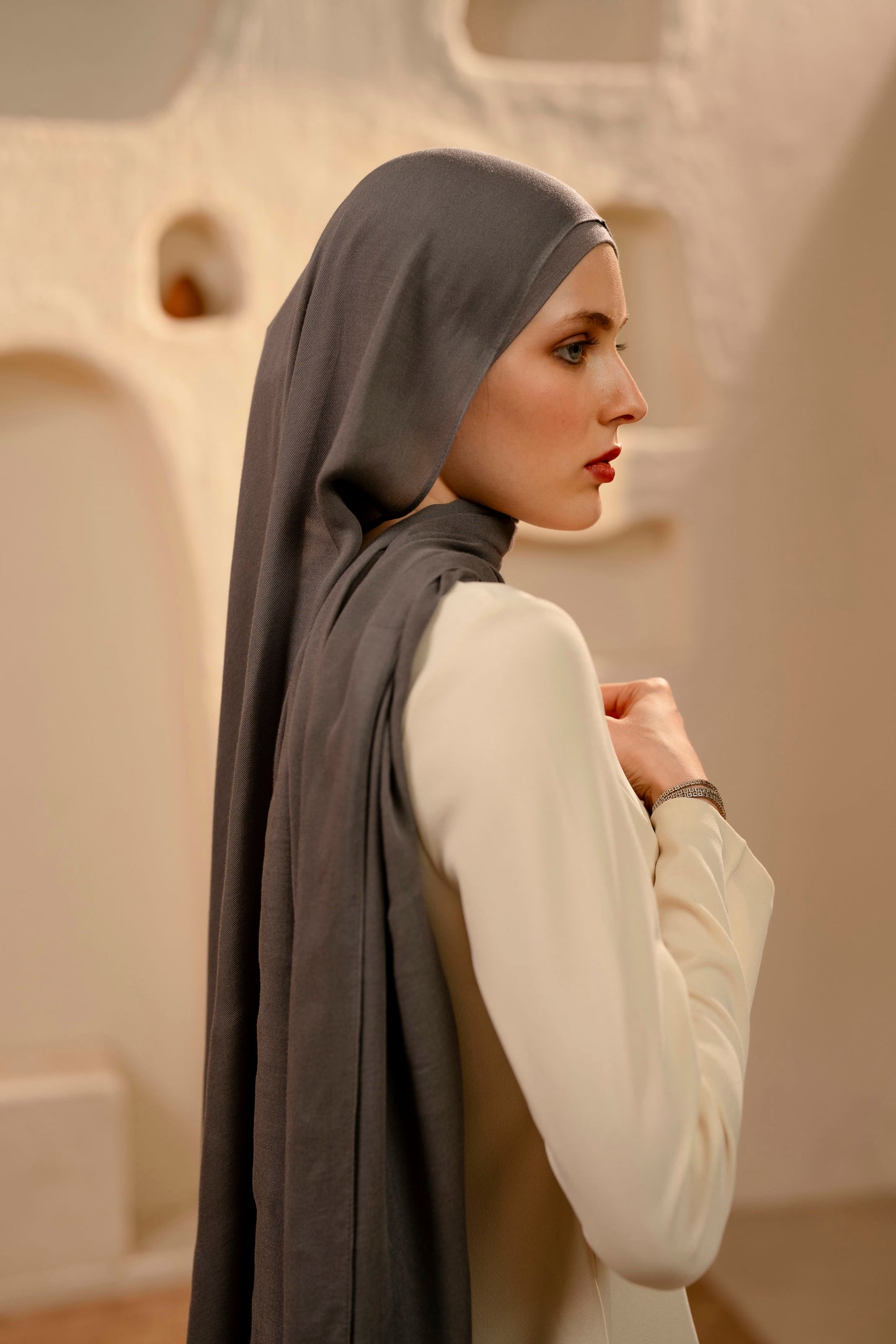 Woman wearing a warm gray hijab in an indoor setting