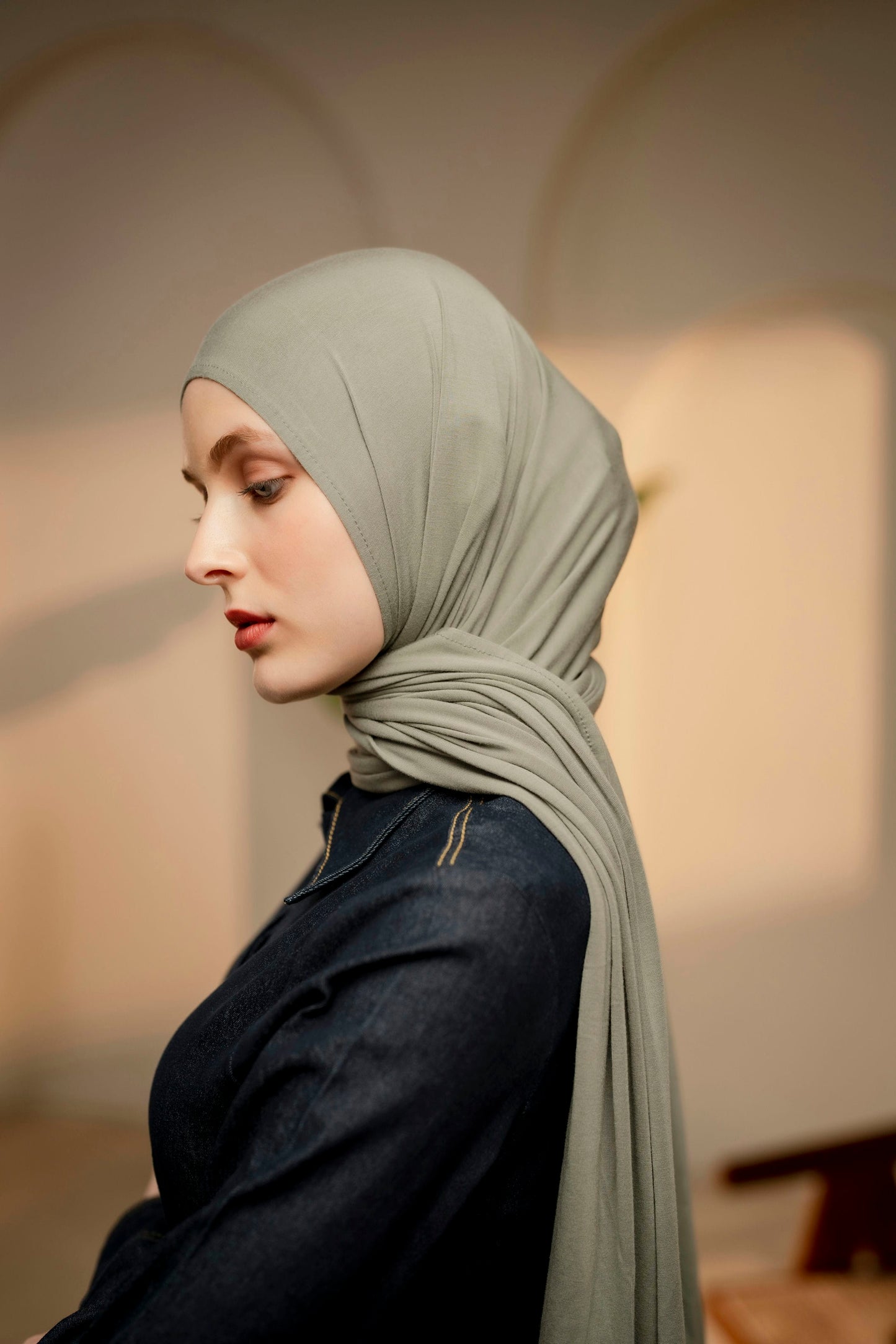 Woman with a side pose wearing a sea green hijab.