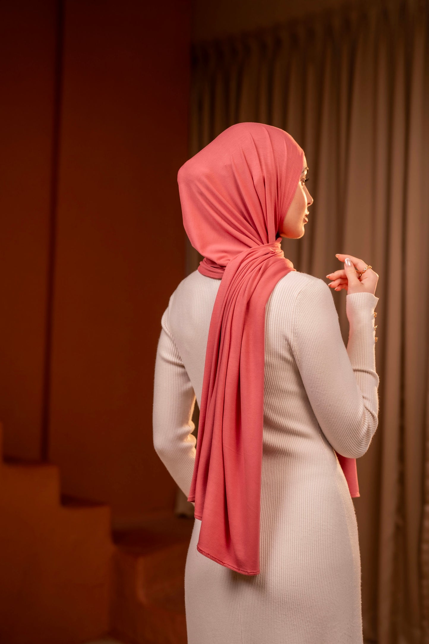 Girl wearing a pink soft premium jersey hijab and light gray outfit in a warm-toned room