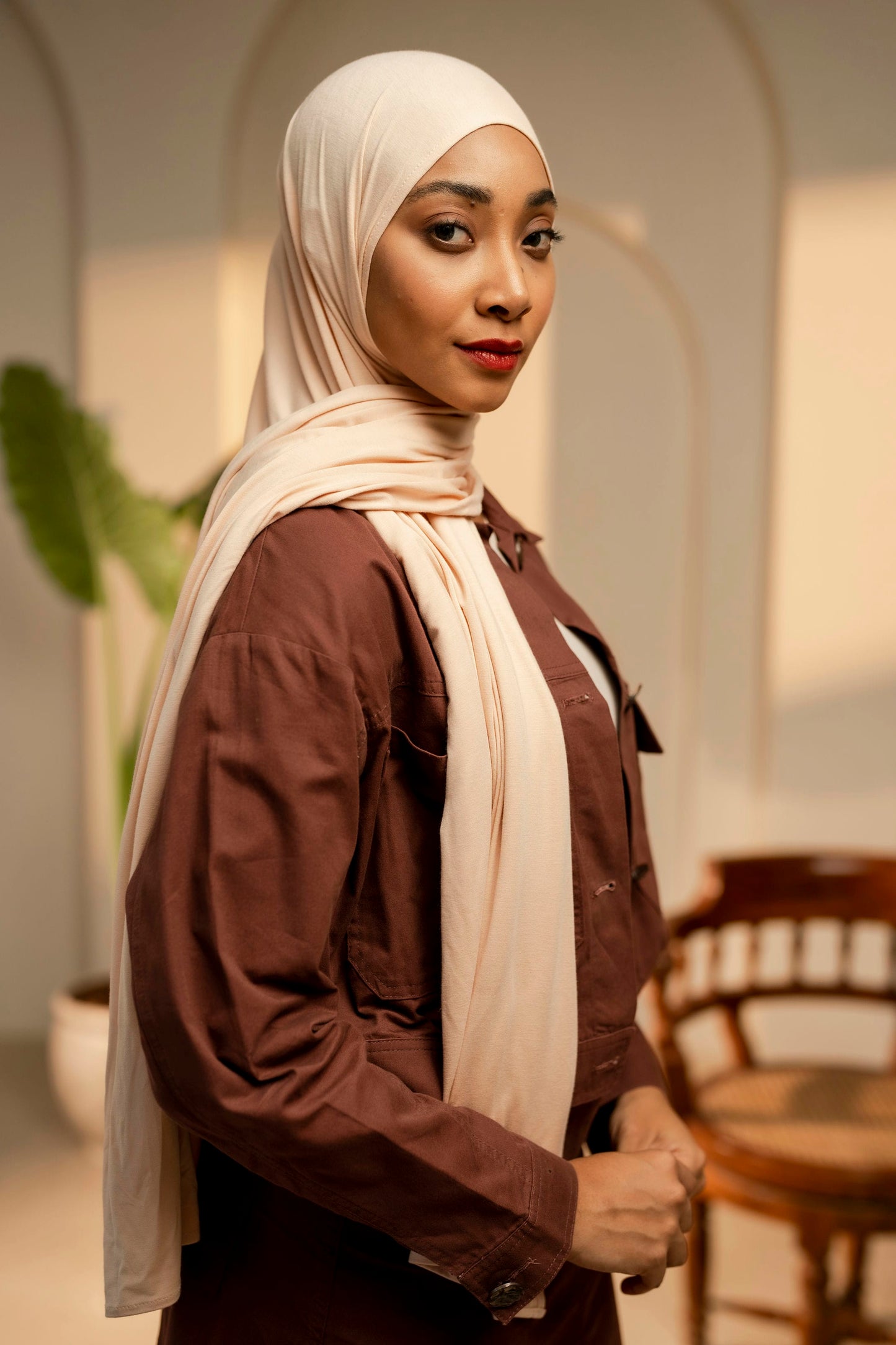 Woman wearing a beige hijab and brown shirt in an indoor setting