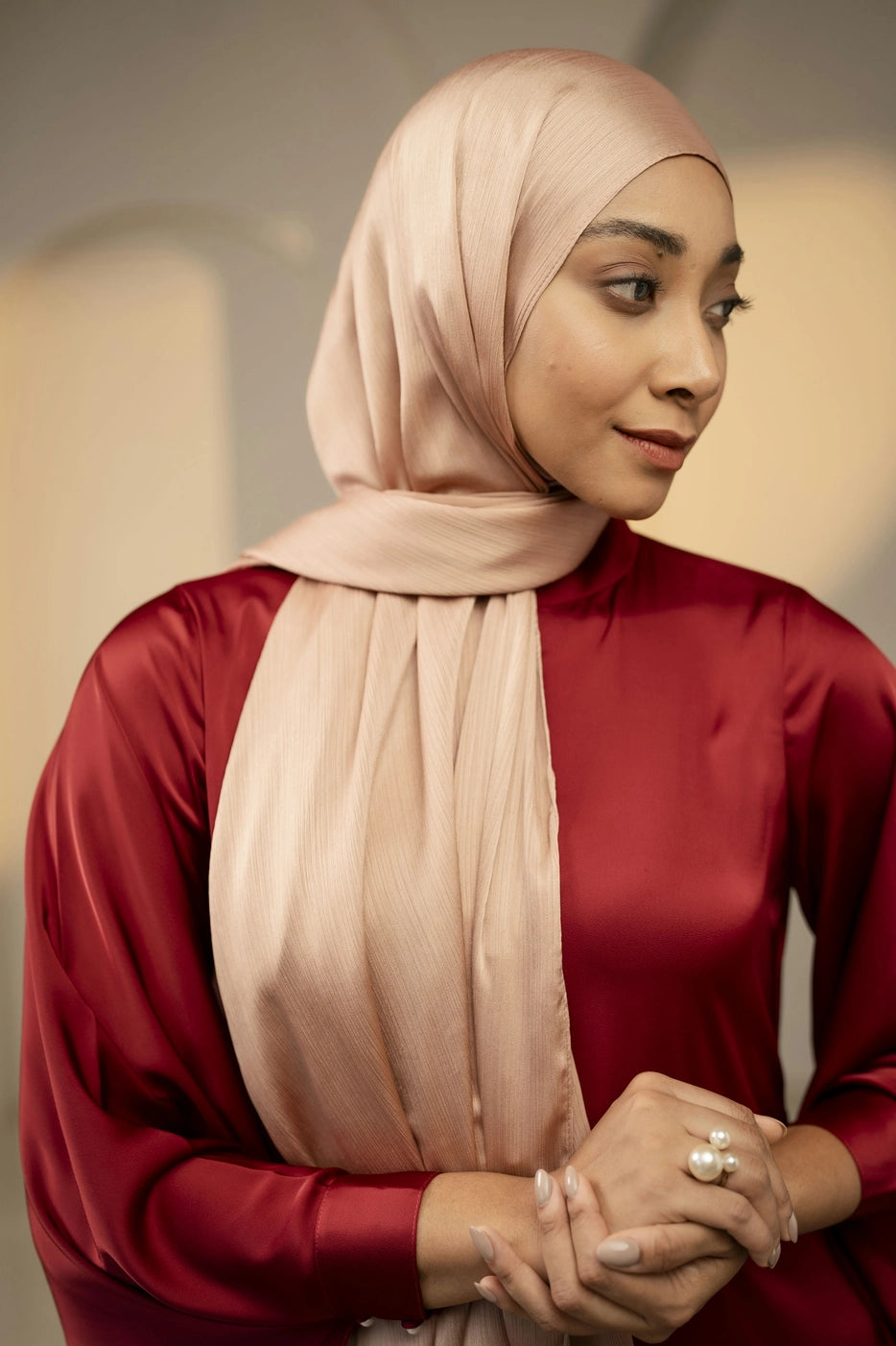 Woman wearing a copper hijab and red top with a blurred background