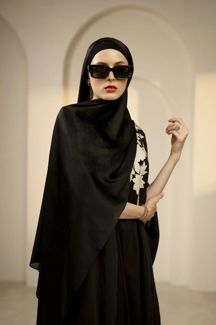 Woman wearing a black hijab and sunglasses in an elegant interior setting