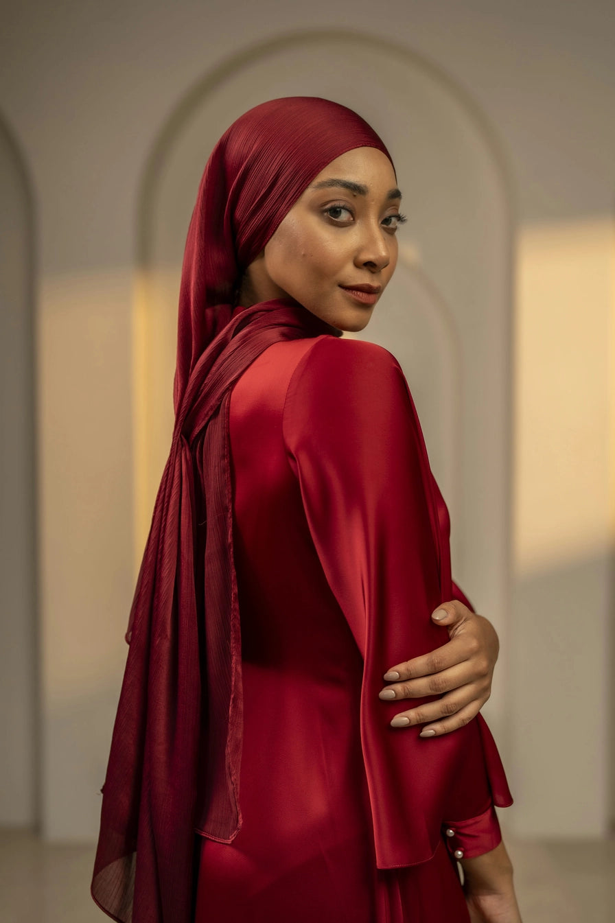 Woman wearing a red hijab and dress in an indoor setting