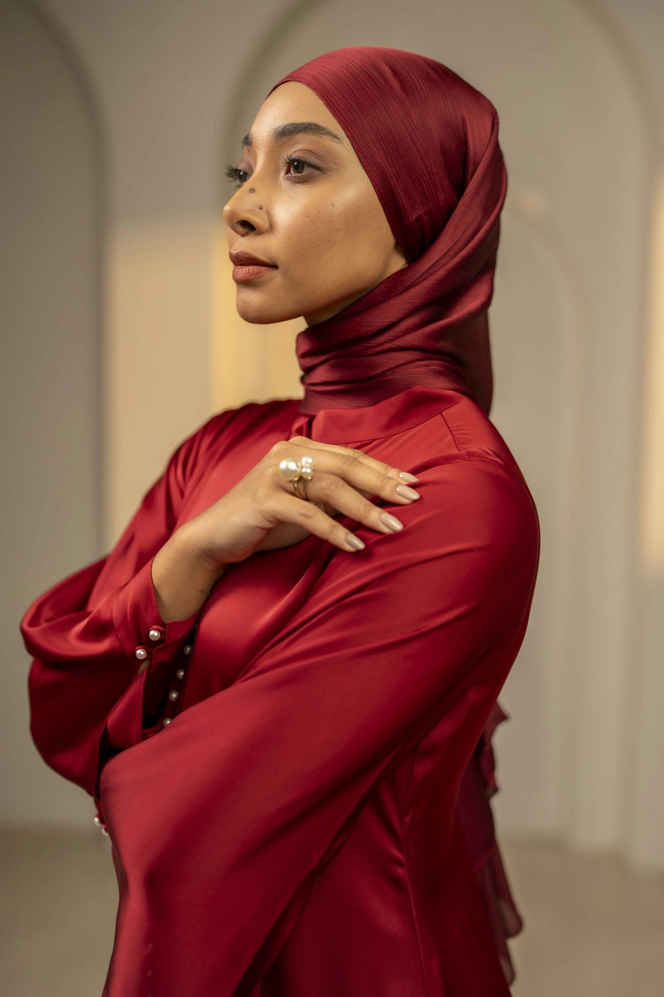 Woman wearing a red hijab and red outfit with a neutral background
