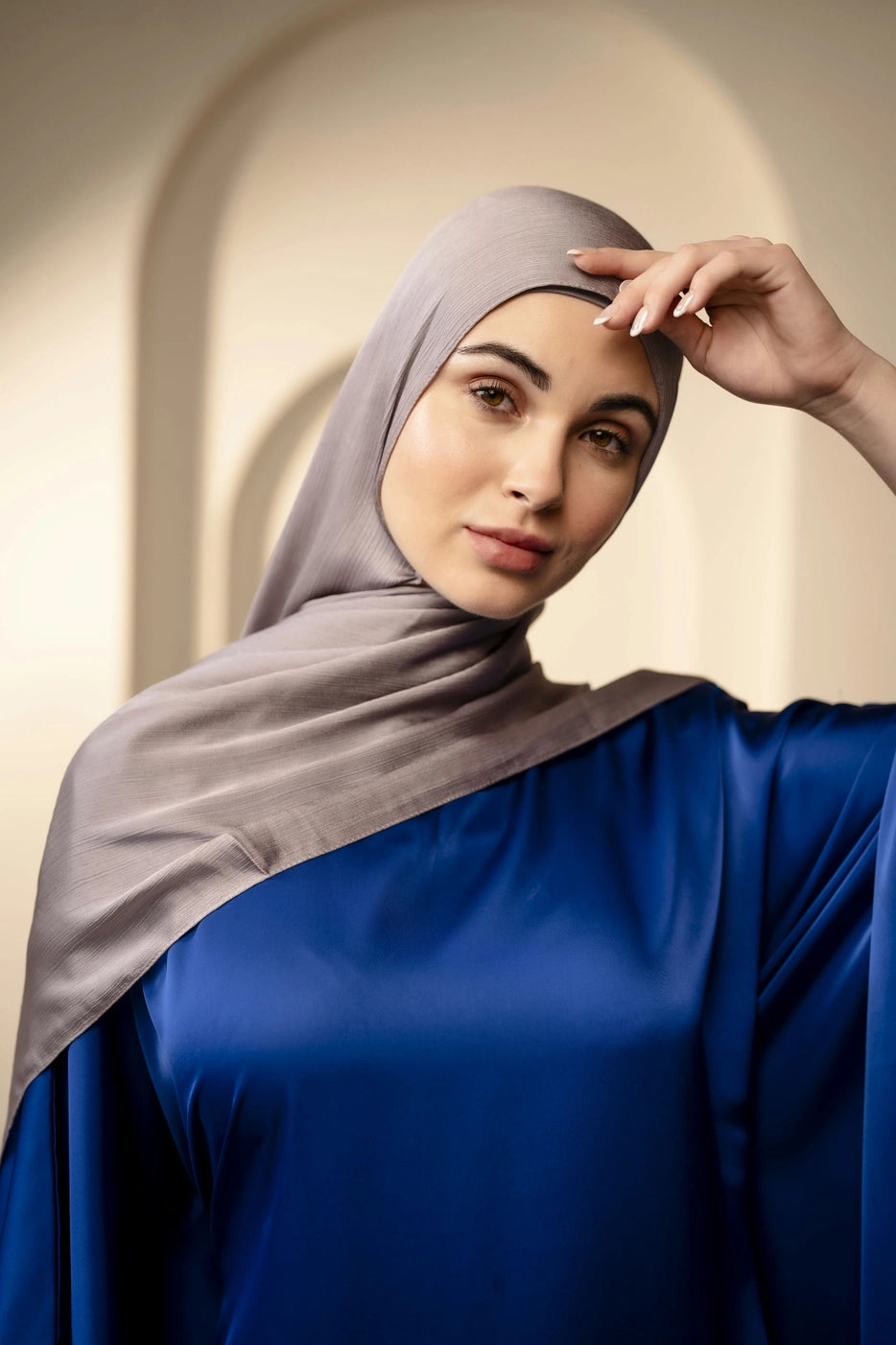 Woman wearing a premium silver gray hijab and navy top against a neutral background