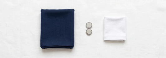 Navy modal hijab, cotton undercap, and silver hijab magnets laid flat on white linen — the essential combination for a polished, secure hijab at a job interview — Hijab Elegance