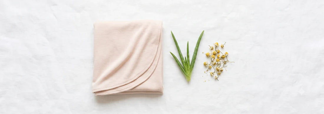 Pale blush bamboo jersey hijab laid next to fresh aloe vera and chamomile on white linen — illustrating gentle, hypoallergenic hijab fabric for sensitive skin — Hijab Elegance