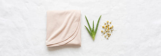 Pale blush bamboo jersey hijab laid next to fresh aloe vera and chamomile on white linen — illustrating gentle, hypoallergenic hijab fabric for sensitive skin — Hijab Elegance
