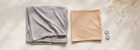 Hijab starter kit flat lay — grey bamboo jersey hijab, nude jersey undercap, and silver hijab magnets on linen