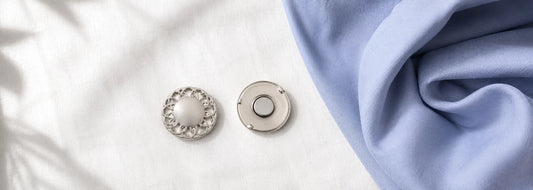Silver hijab magnet set — front and back pieces shown separately alongside a folded cotton candy blue hijab, demonstrating how they snap together through fabric — Hijab Elegance