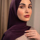 Woman wearing a dark purple hijab against a neutral background - plum