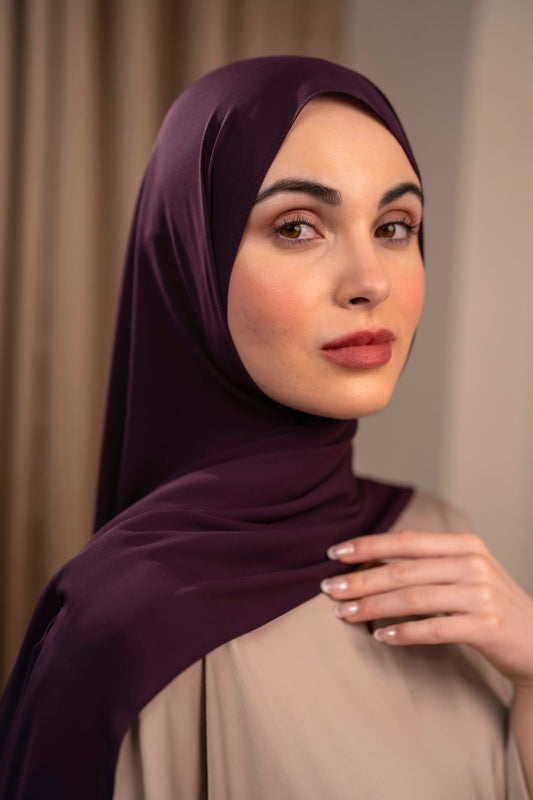 Woman wearing a dark purple hijab against a neutral background - plum