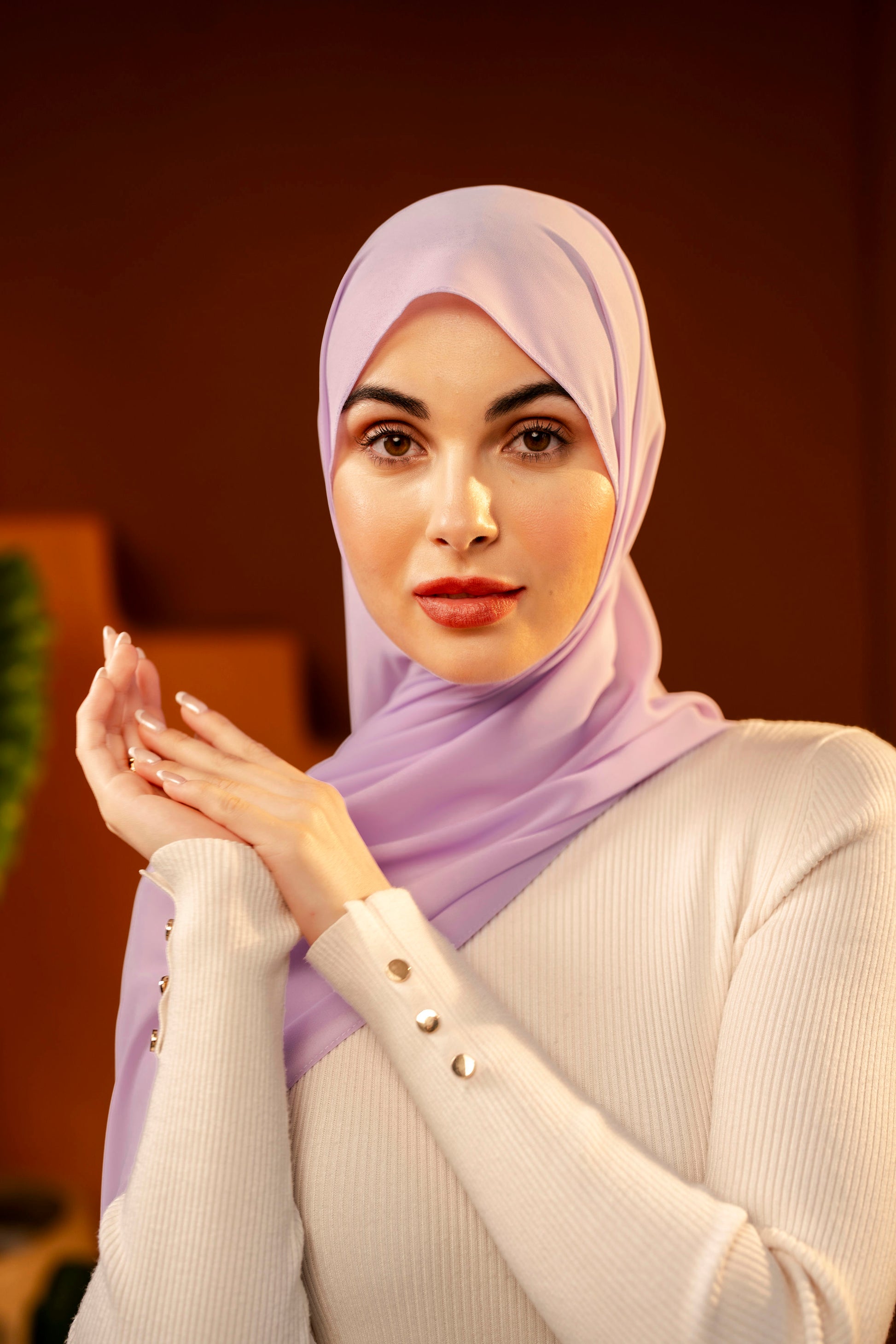 Woman wearing a light purple hijab and white sweater against a warm-toned background - Lavender