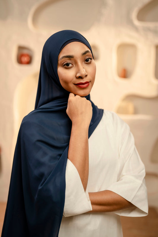 Woman wearing a dark blue hijab and white outfit against a neutral background - Navy