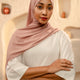 Woman wearing a pink hijab and white outfit in an abstract architectural setting - dusty pink