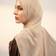 Woman wearing a beige hijab against a plain background - nude