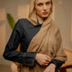 Woman wearing a beige hijab and dark shirt in an indoor setting - caramel