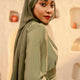 Woman wearing a green hijab and matching outfit in a neutral setting - olive green