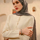 Woman wearing a warm gray hijab and cream outfit in an indoor setting
