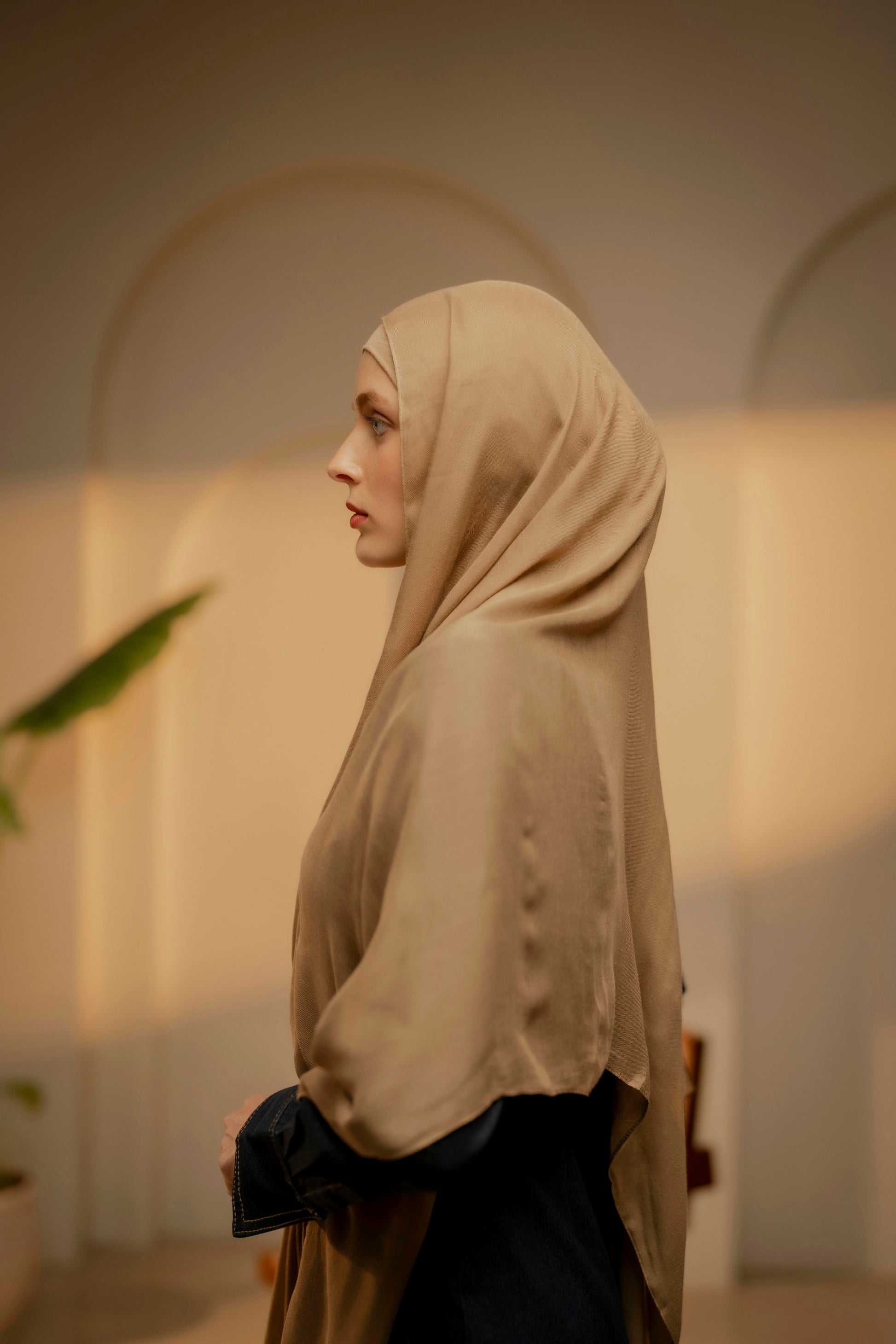 Woman wearing a beige hijab in an indoor setting with soft lighting - caramel