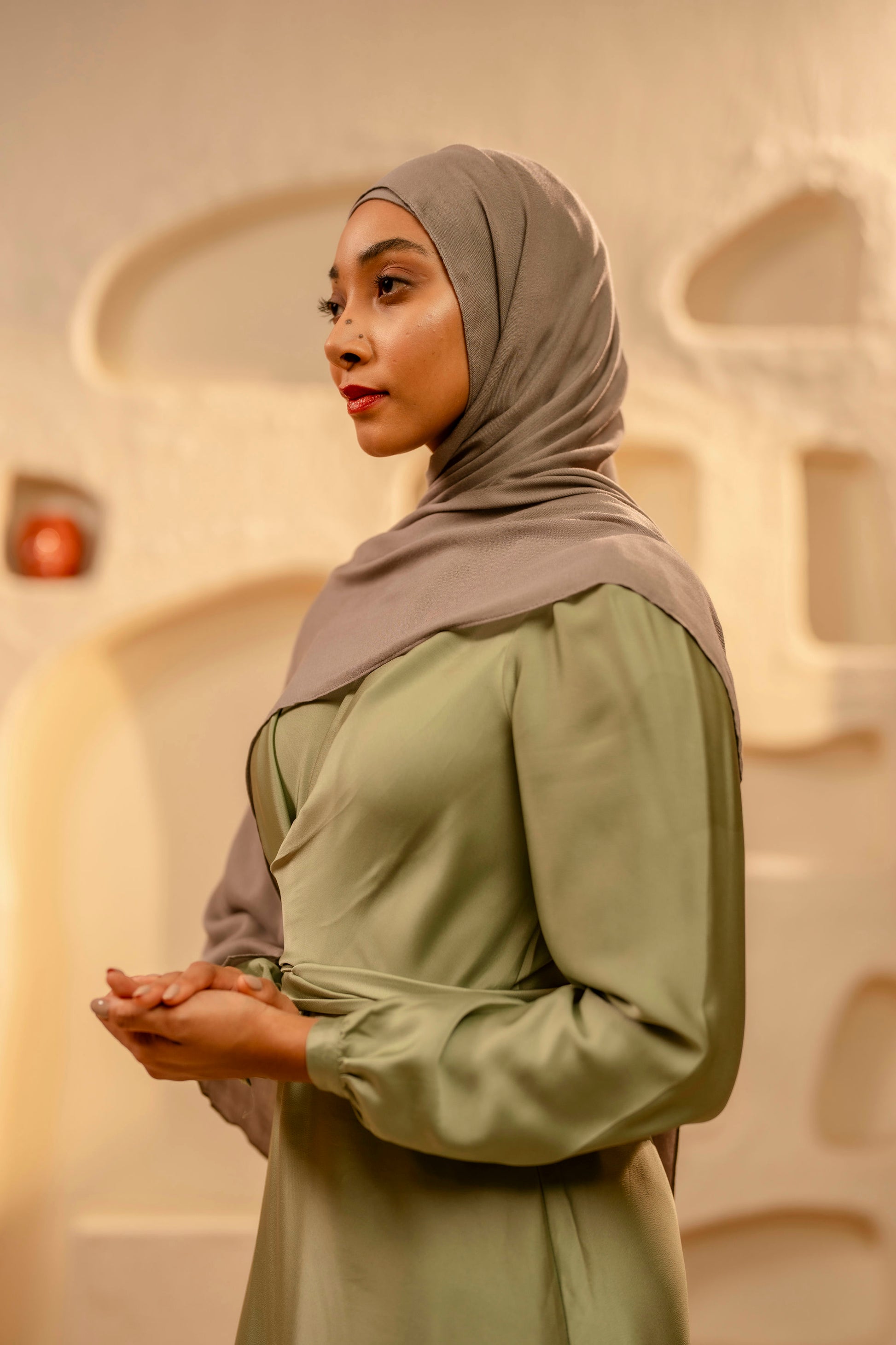 Woman wearing a hijab and green outfit in an indoor setting - khaki