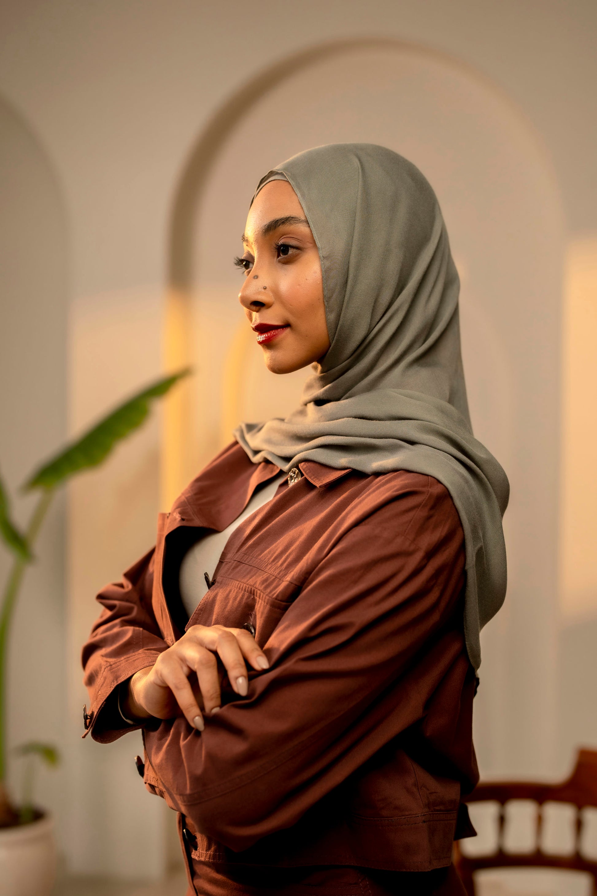 Woman wearing a hijab and brown jacket in an indoor setting - sage green