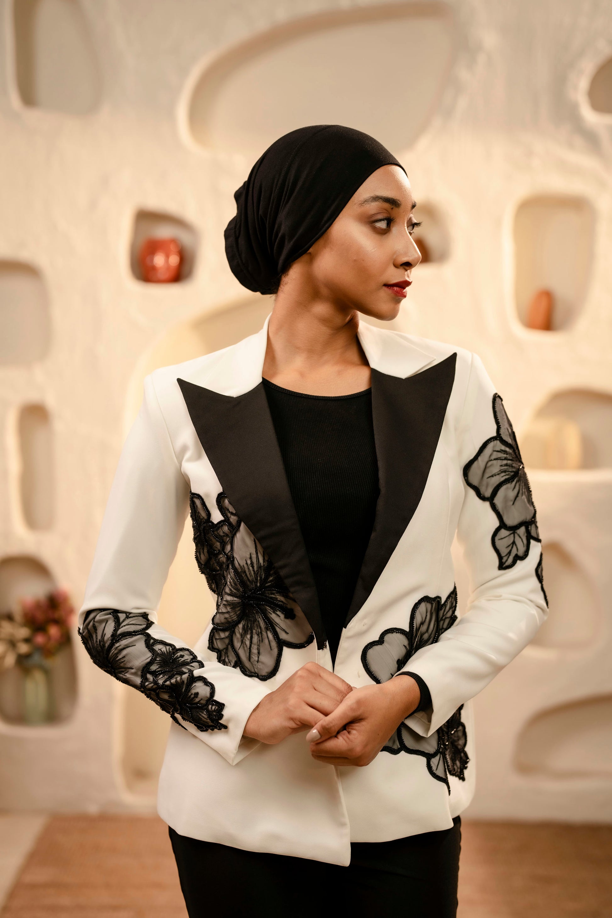 Woman wearing a white blazer with black butterfly patterns in an indoor setting