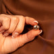 Rose gold hijab magnets on a hand against a brown fabric background