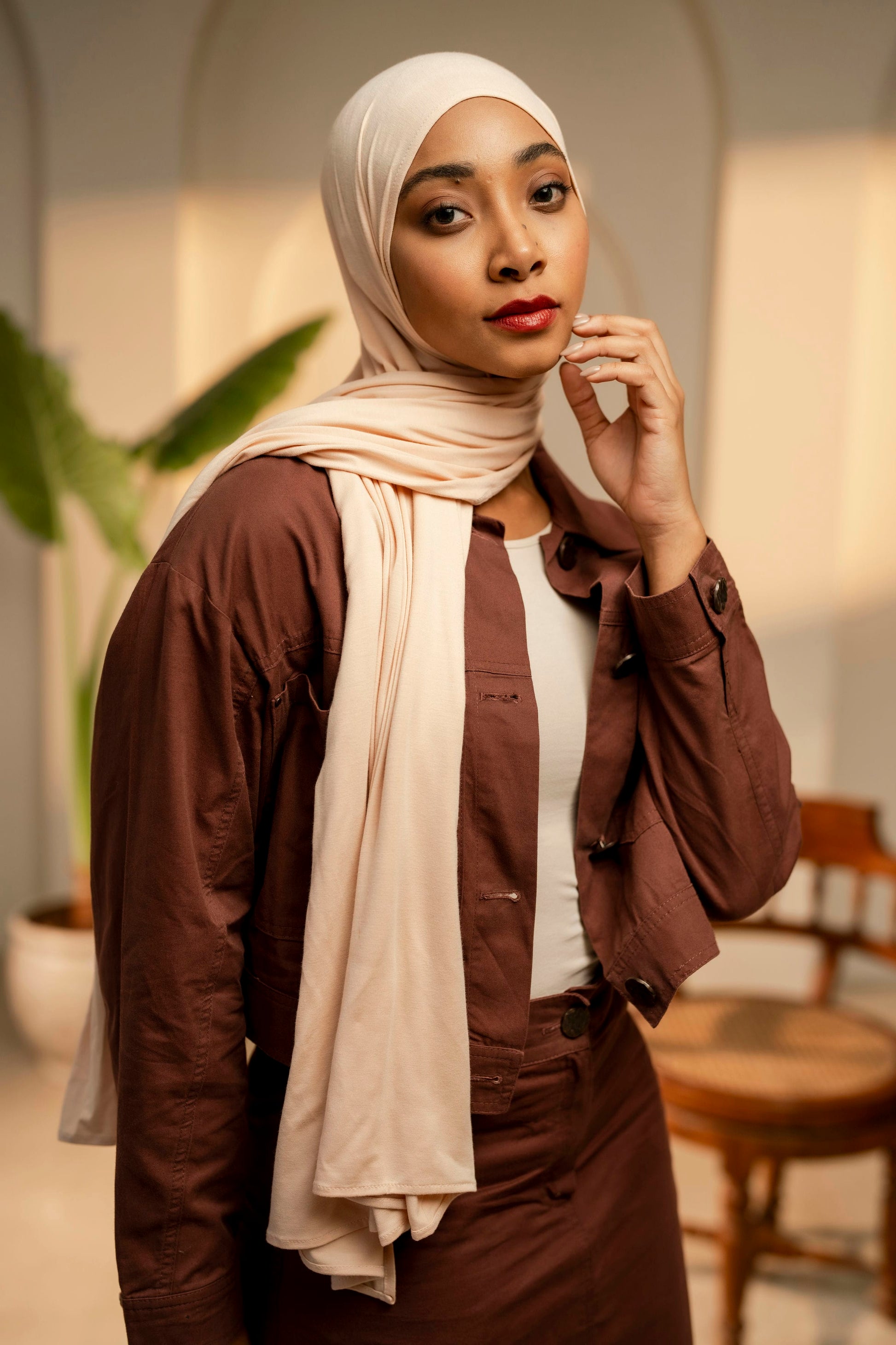Woman wearing a brown outfit with a beige hijab in an indoor setting