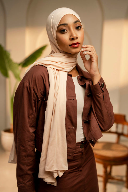 Woman wearing a brown outfit with a beige hijab in an indoor setting