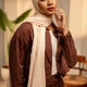 Woman wearing a brown outfit with a beige hijab in an indoor setting