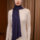 Woman wearing a denim blue hijab and white outfit against a brown curtain background
