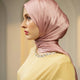 Woman wearing a pink hijab and yellow top against a neutral background
